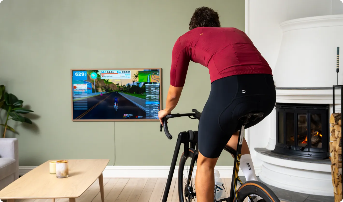 Biking on a roller in front of a TV showing the UI of Zwift